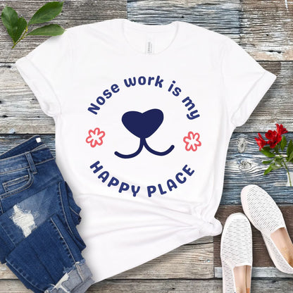 White nosework for dogs t-shirt with 'Nose work is my happy place' text with dog nose design, shown on a wooden surface with jeans and shoes.