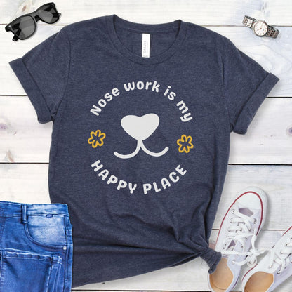 Heather navy nosework for dogs t-shirt with 'Nose work is my happy place' text with dog nose design, shown on a wooden surface with jeans and shoes.