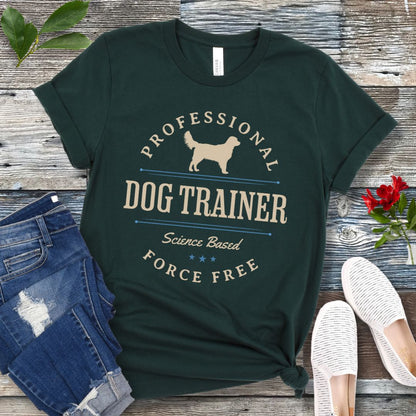 Dark green dog training t-shirt with the text 'PROFESSIONAL DOG TRAINER, Science Based, Force Free"' and custom dog breed silhouette in a vintage, badge style design. The shirt is displayed flat with a pair of blue jeans and white shoes.