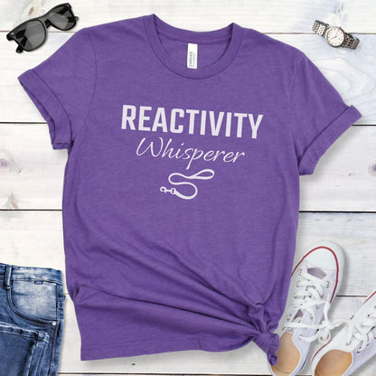 Purple unisex t-shirt featuring a Reactivity Whisperer  text design with leash graphic, a funny reactive dog trainer shirt for dog training professionals.