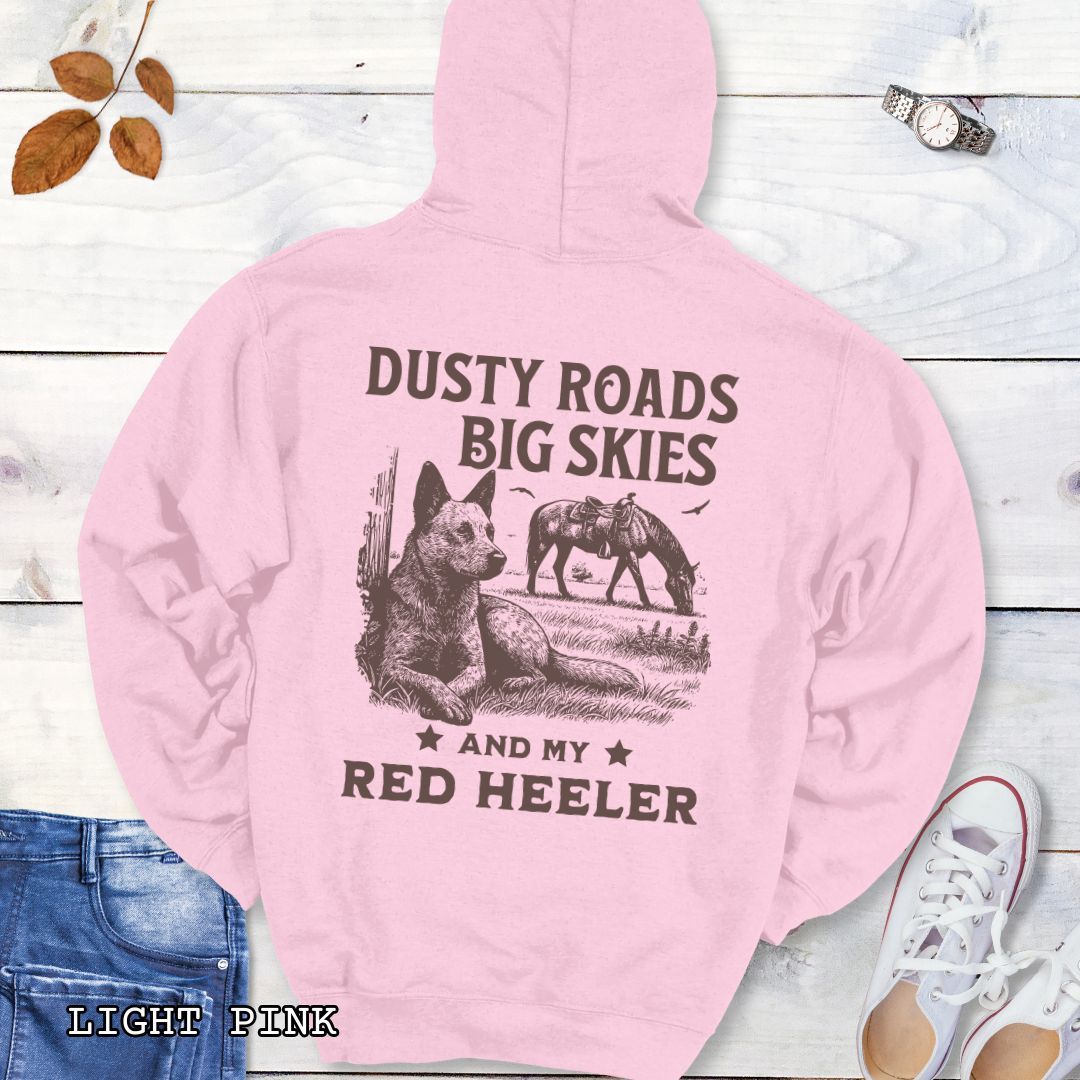 Back view of a light pink Red Heeler hoodie featuring a Western-style design with grazing horse, rustic fence, and an Cattle Dog illustration; text reads “Dusty Roads, Big Skies, and My Red Heeler.”