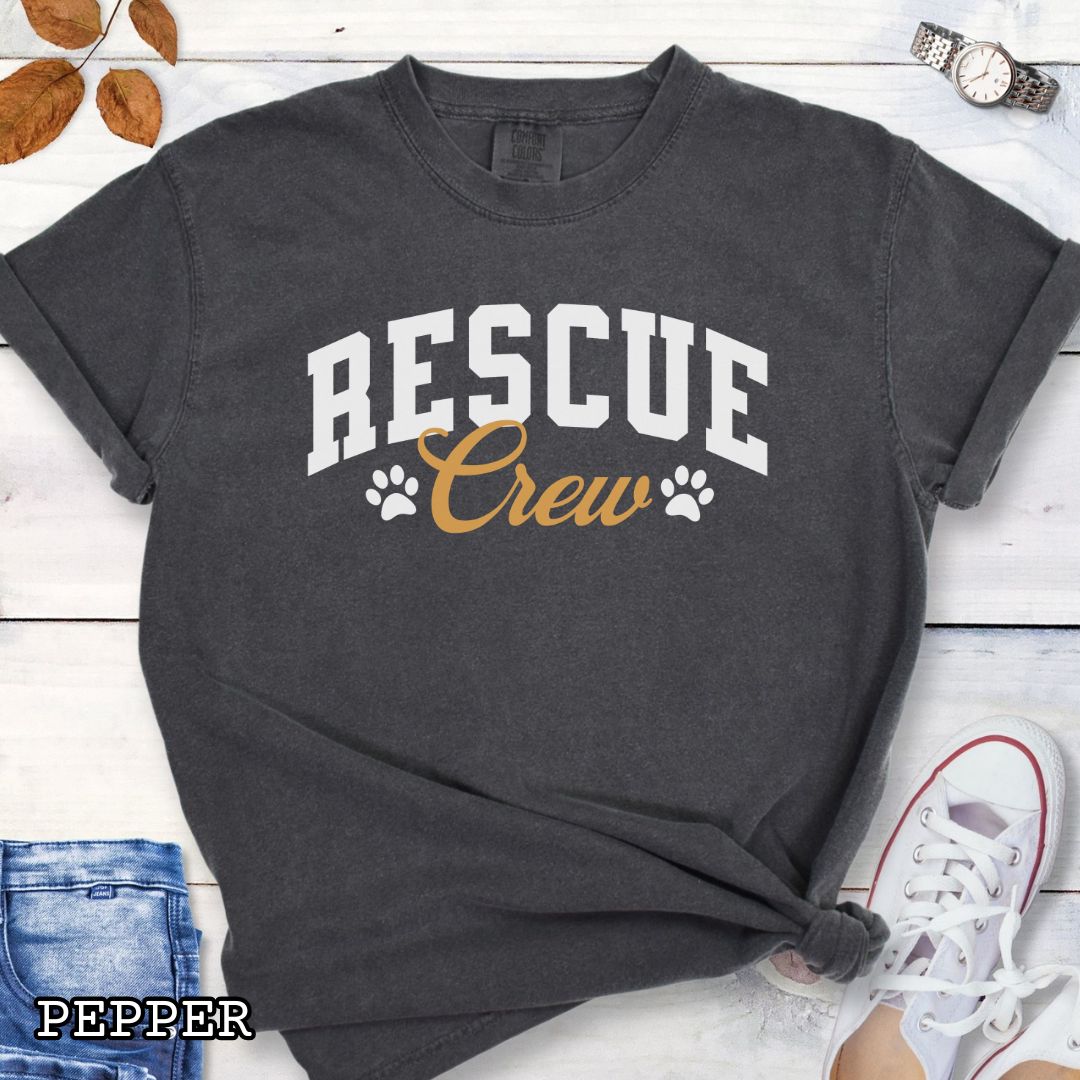 Dark grey Comfort Colors t-shirt featuring bold college-style Rescue Crew text with paw prints, perfect for rescue dog lovers, dog adoption advocates, fosters, and rescue volunteers.