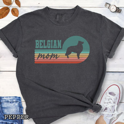Dark grey Comfort Colors t-shirt for Belgian Sheepdog lovers with retro stripe design, Belgian silhouette and 'Belgian Mom' text, shown on a wooden surface with jeans and shoes.