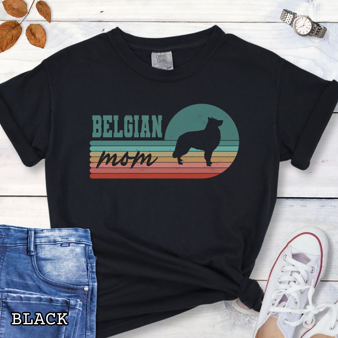 Black Comfort Colors t-shirt for Belgian Sheepdog lovers with retro stripe design, Belgian silhouette and 'Belgian Mom' text, shown on a wooden surface with jeans and shoes.