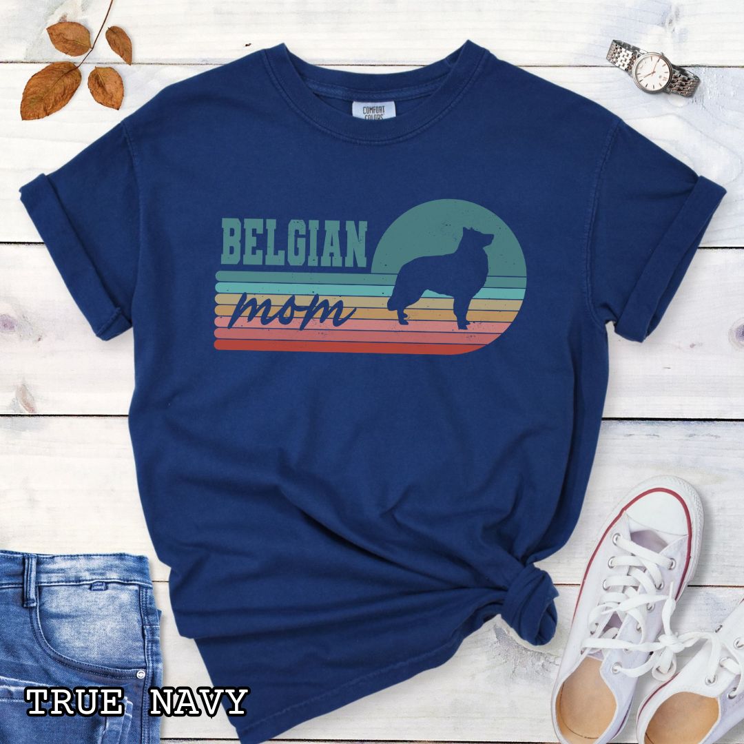 Navy blue Comfort Colors t-shirt for Belgian Sheepdog lovers with retro stripe design, Belgian silhouette and 'Belgian Mom' text, shown on a wooden surface with jeans and shoes.