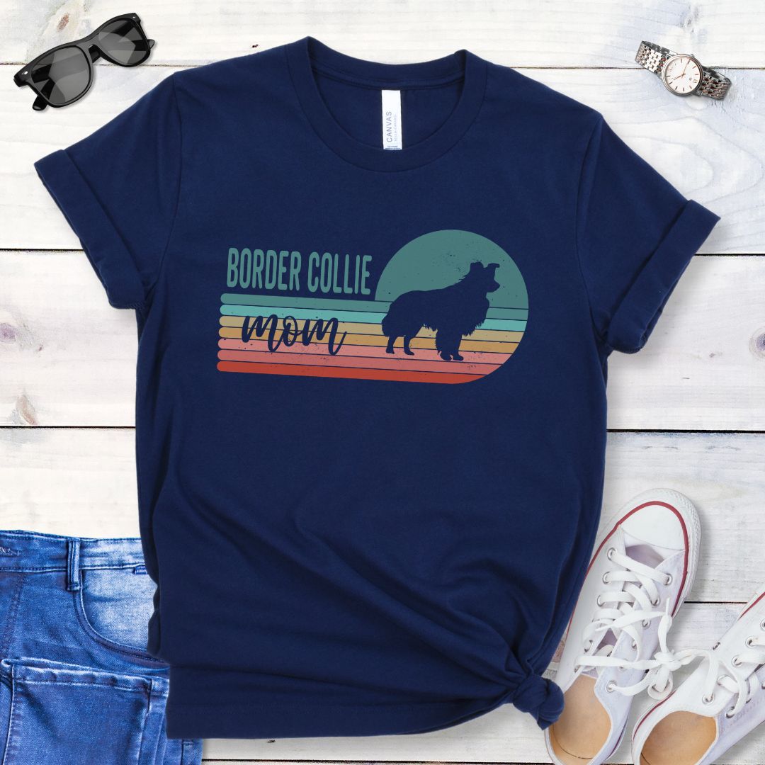 Navy t-shirt with retro style 'Border Collie Mom' design on a wooden surface with jeans and shoes.