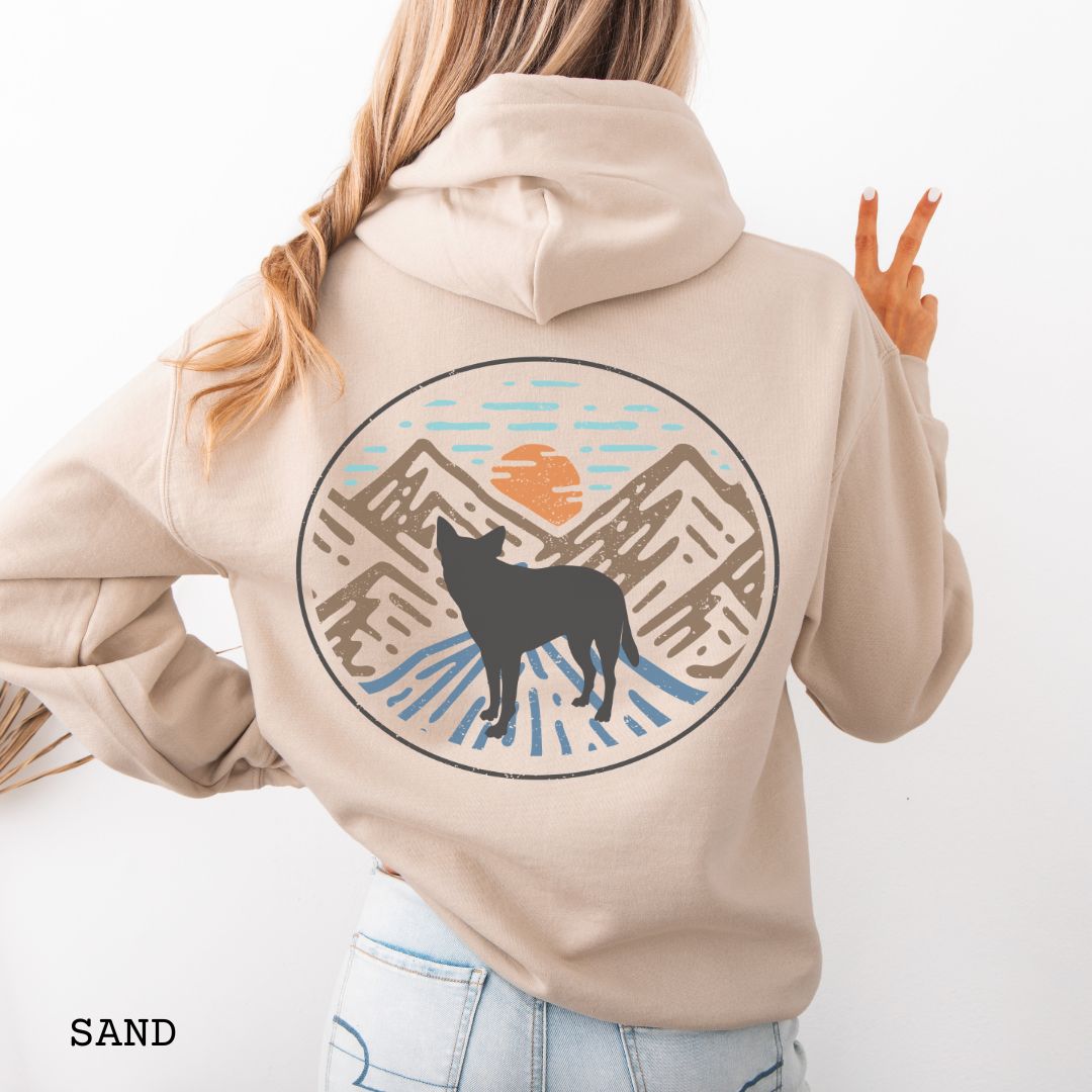 Beige Cattle Dog hoodie with a Heeler and retro mountain design on the back, worn by a person.