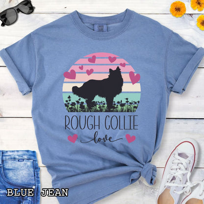 Blue Comfort Colors t-shirt with colorful vintage sunset design with hearts, flowers, and Rough Collie silhouette and the text 'Rough Collie Love', shown on a wooden surface.
