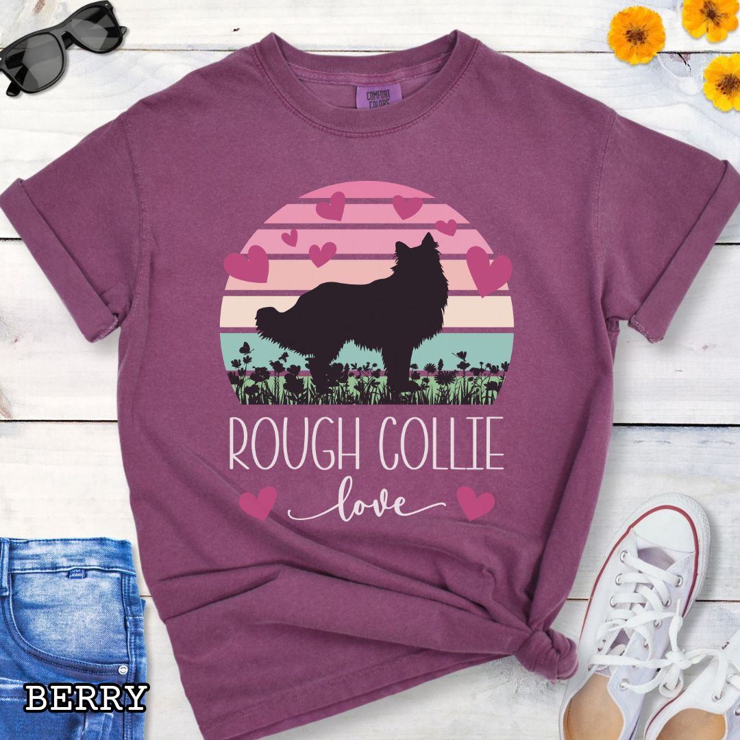 Berry Comfort Colors t-shirt with colorful vintage sunset design with hearts, flowers, and Rough Collie silhouette and the text 'Rough Collie Love', shown on a wooden surface.