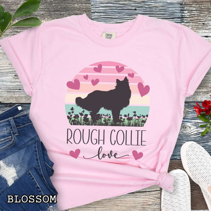 Pink Comfort Colors t-shirt with colorful vintage sunset design with hearts, flowers, and Rough Collie silhouette and the text 'Rough Collie Love', shown on a wooden surface.