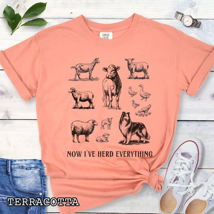 Orange Comfort Colors t-shirt for Rough Collie lovers with vintage farm animal illustrations and a Rough Collie dog, with the humorous text 'Now I've Herd Everything', shown on a wooden surface with denim jeans and flowers.