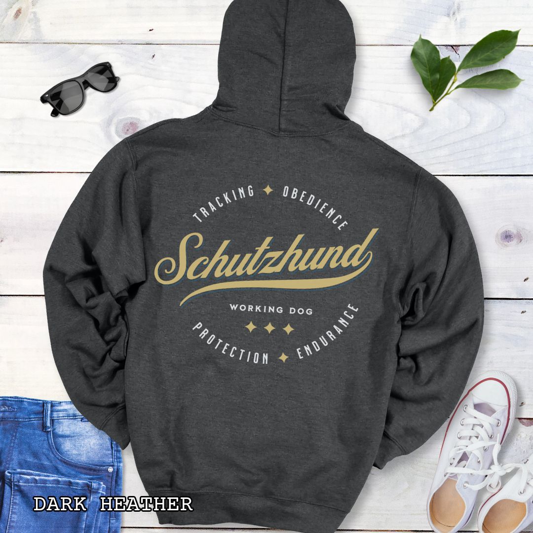 Back view of a dark grey unisex Schutzhund/IGP hoodie with vintage style text design that reads 'Schutzhund, Working Dog, Tracking, Obedience, Protection, Endurance'. Presented on a wooden background with jeans and shoes.