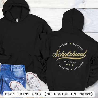 Back view of a black unisex Schutzhund/IGP hoodie with vintage style text design that reads 'Schutzhund, Working Dog, Tracking, Obedience, Protection, Endurance'. Presented on a wooden background with jeans and shoes.