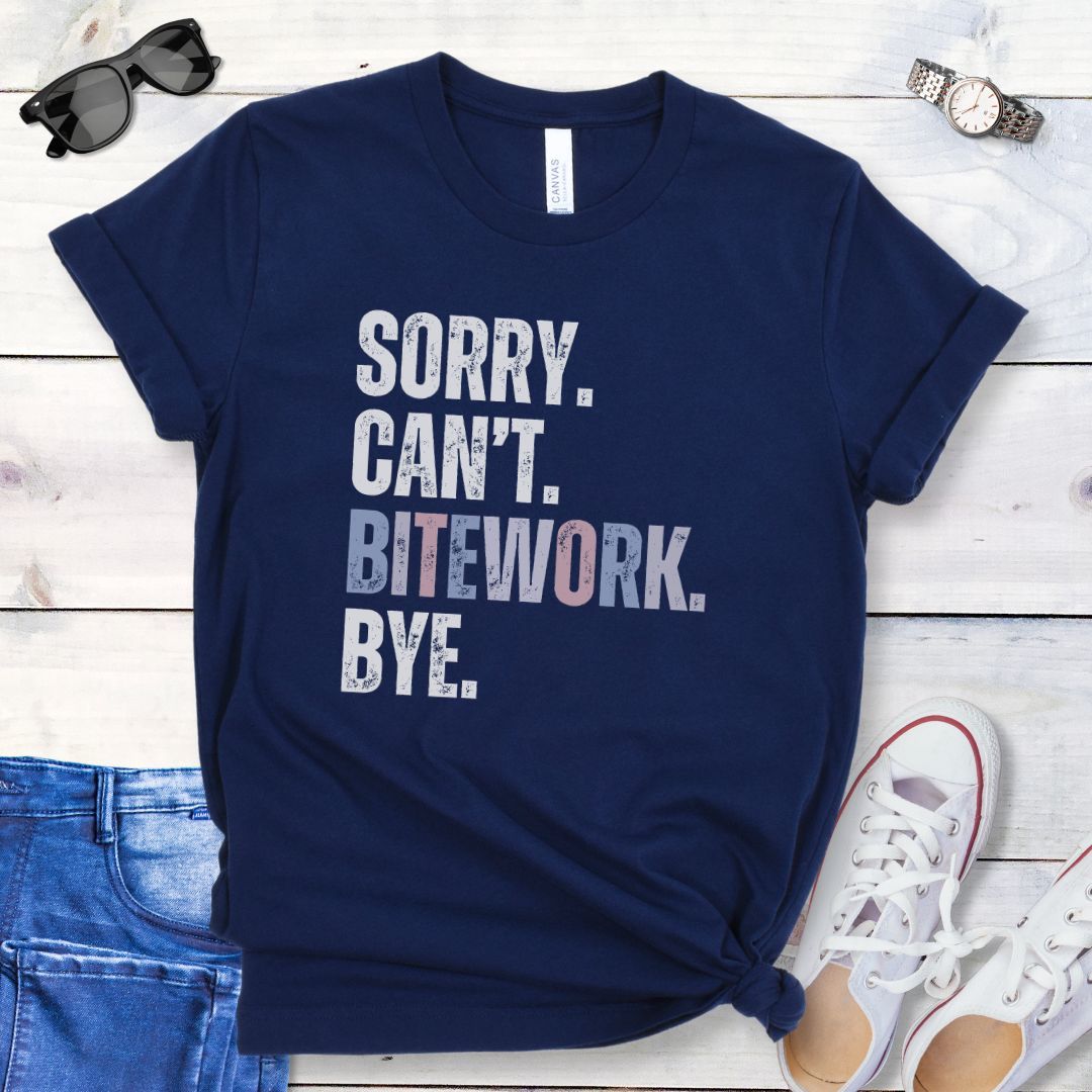 Navy protection dog training t-shirt with colorful, distressed text 'SORRY. CAN'T. BITEWORK. BYE.', presented on a wooden surface with jeans and shoes.