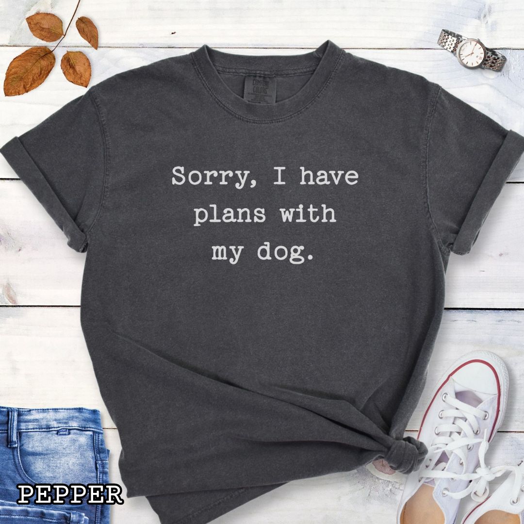 Dark gray Comfort Colors dog lover t-shirt with 'Sorry, I have plans with my dog' text on a wooden surface with shoes and jeans.