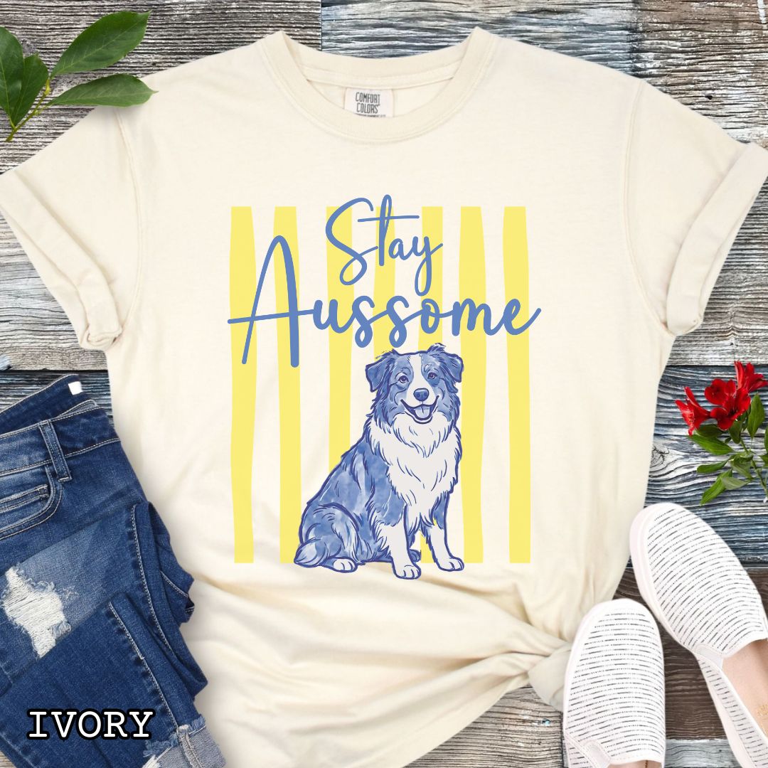 Beige Comfort Colors Australian Shepherd t-shirt featuring Stay Aussome slogan with cute blue merle Aussie illustration, perfect for Aussie moms, herding dog lovers, and Australian Shepherd gifts.