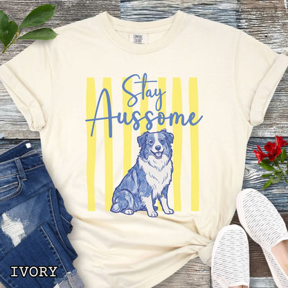 Beige Comfort Colors Australian Shepherd t-shirt featuring Stay Aussome slogan with cute blue merle Aussie illustration, perfect for Aussie moms, herding dog lovers, and Australian Shepherd gifts.