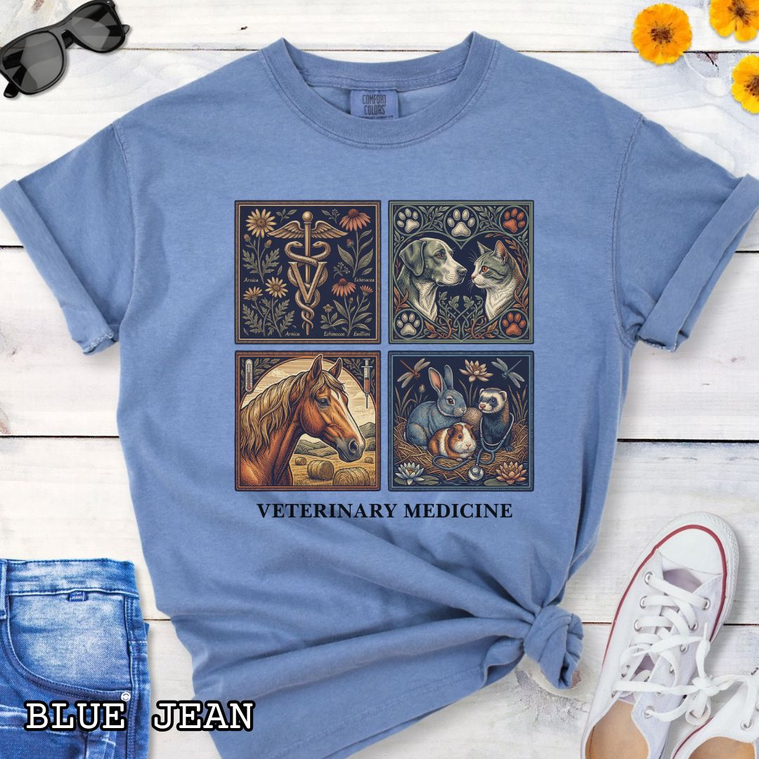 Blue Comfort Colors t-shirt with vintage linocut-style veterinary-themed design in four panels and the text 'Veterinary Medicine', shown on a wooden surface with jeans and flowers.