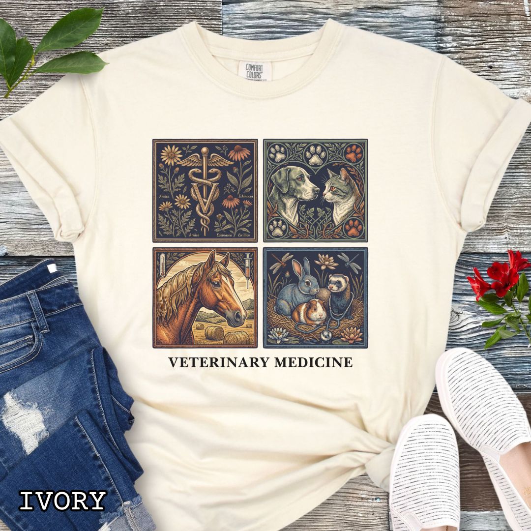 Beige Comfort Colors t-shirt with vintage linocut-style veterinary-themed design in four panels and the text 'Veterinary Medicine', shown on a wooden surface with jeans and flowers.