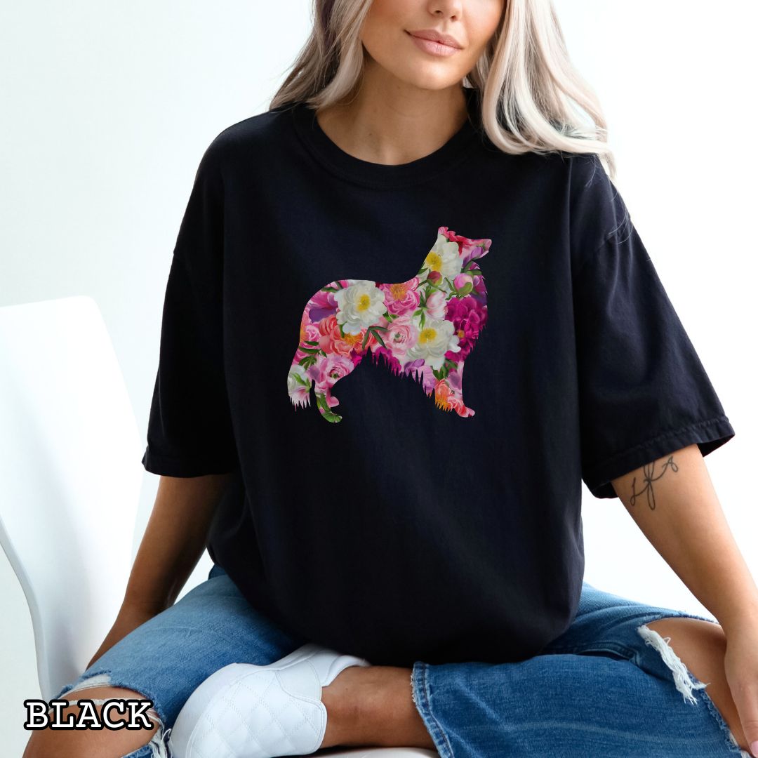 Person wearing a black Comfort Colors t-shirt for Collie lovers with floral Rough Collie dog design, shown on a wooden surface with jeans and flowers.