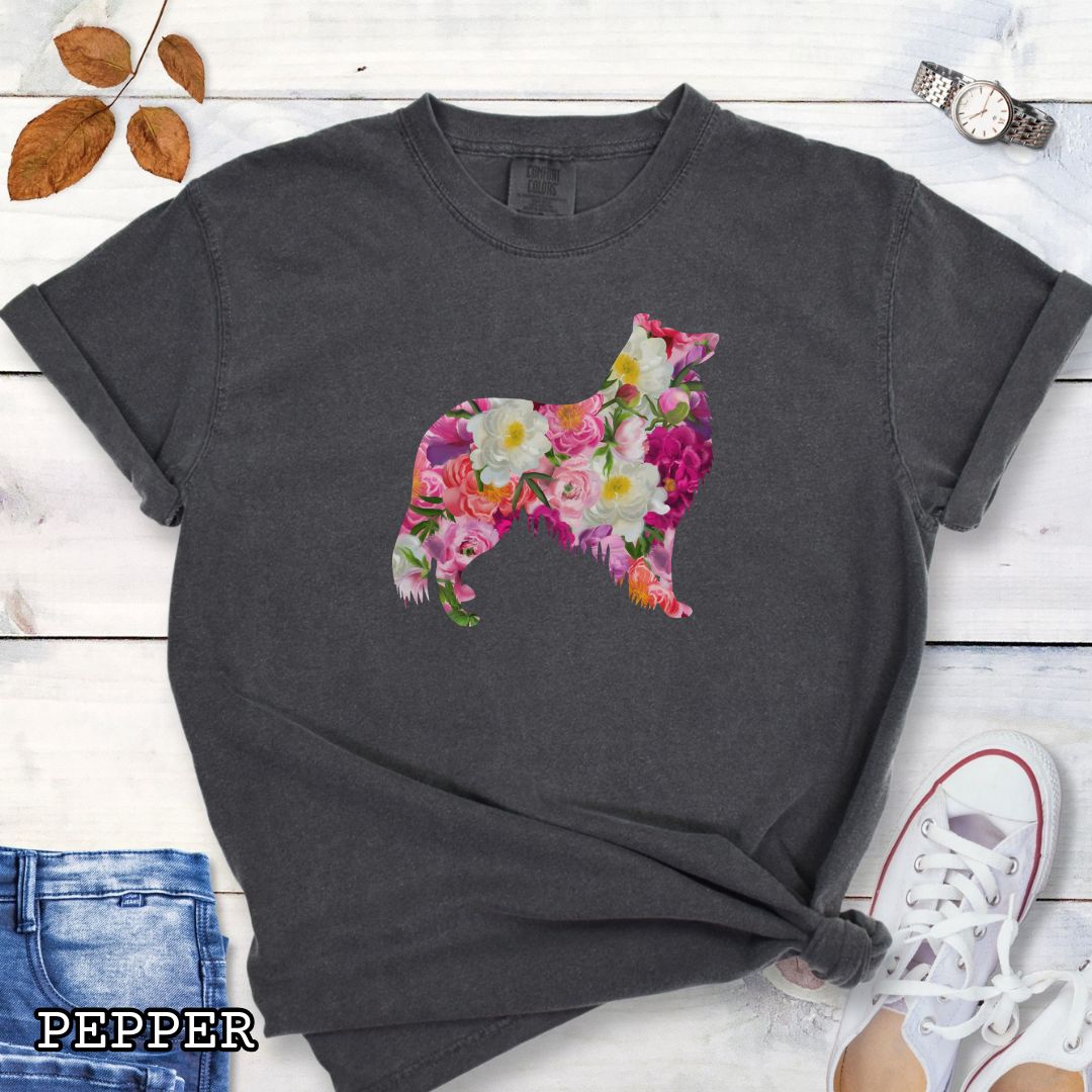 Dark grey Comfort Colors t-shirt for Collie lovers with floral Rough Collie dog design, shown on a wooden surface with jeans and flowers.