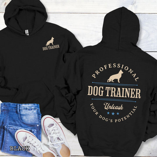 Front and back view of a black dog training hoodie with the text 'PROFESSIONAL DOG TRAINER, Unleash Your Dog's Potential"' and custom dog breed silhouette in a vintage, badge style design. The shirt is displayed flat with a pair of blue jeans and white shoes.