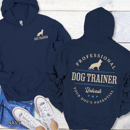 Front and back view of a navy dog training hoodie with the text 'PROFESSIONAL DOG TRAINER, Unleash Your Dog's Potential"' and custom dog breed silhouette in a vintage, badge style design. The shirt is displayed flat with a pair of blue jeans and white shoes.