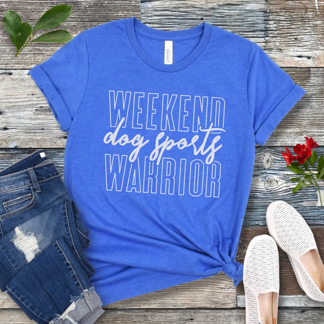 A royal blue dog training t-shirt with the text 'Weekend dog sports warrior' printed in white, displayed flat with a pair of blue jeans and white shoes.