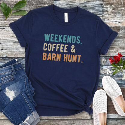 Navy blue dog sports t-shirt with 'Weekends, Coffee & Barn Hunt' in bold, colorful text, presented on a wooden surface with jeans and shoes.