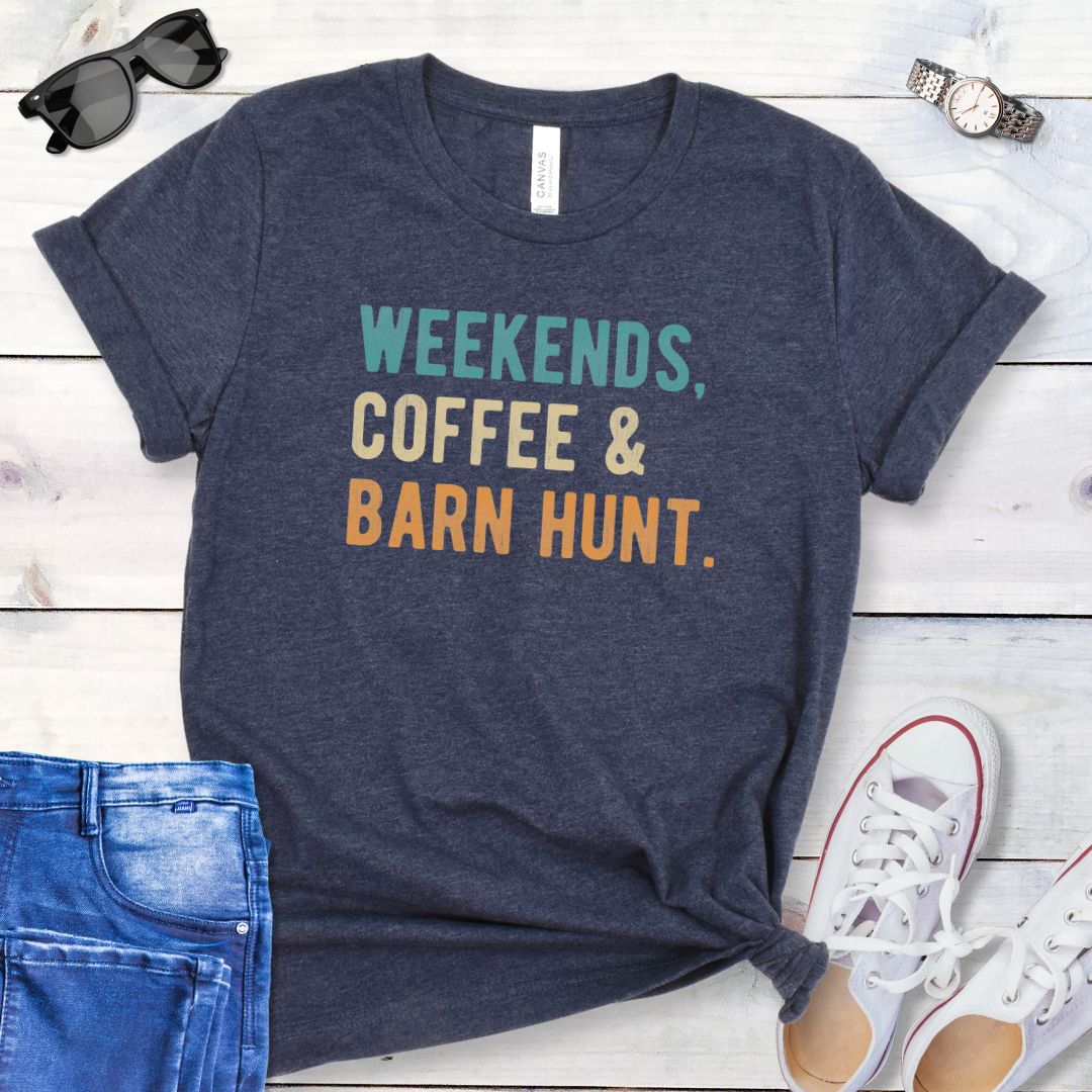 Heather navy dog sports t-shirt with 'Weekends, Coffee & Barn Hunt' in bold, colorful text, presented on a wooden surface with jeans and shoes.