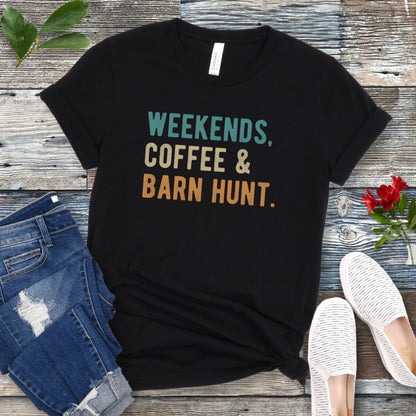Black dog sports t-shirt with 'Weekends, Coffee & Barn Hunt' in bold, colorful text, presented on a wooden surface with jeans and shoes.