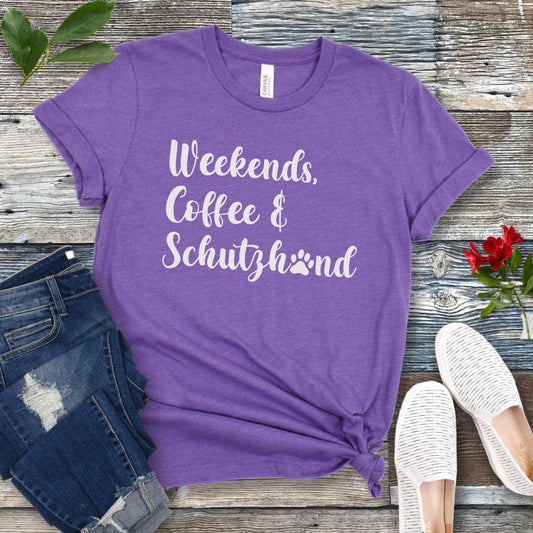 Purple t-shirt with 'Weekends, Coffee & Schutzhund' text on a wooden surface with jeans and shoes.