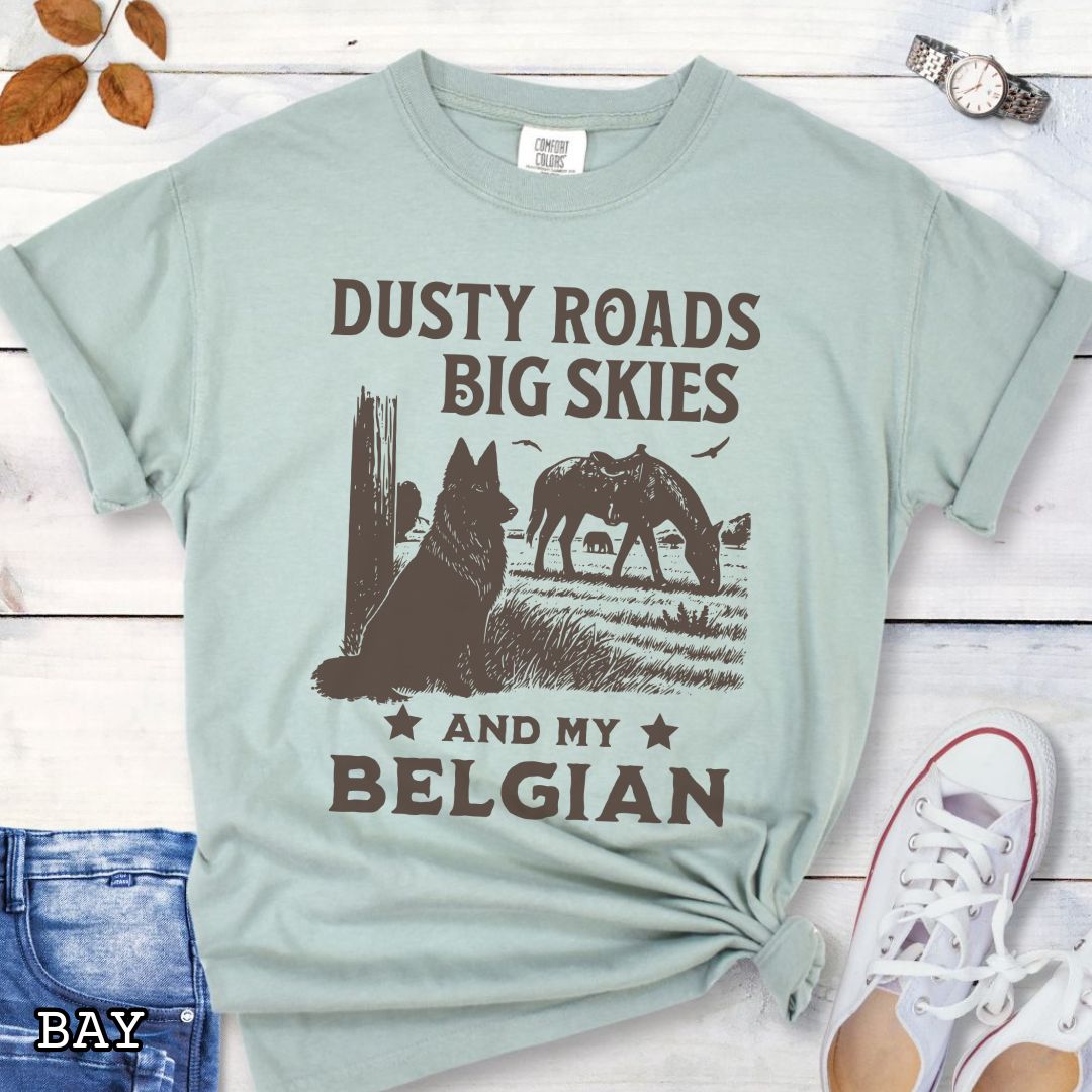 Light green Comfort Colors t-shirt featuring a Western-style design with grazing horse, rustic fence, and a Belgian Sheepdog illustration; text reads “Dusty Roads, Big Skies, and My Belgian.”