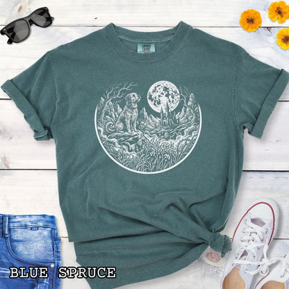 Green Comfort Colors t-shirt featuring a Gothic moonlit scene with dog, castle and graveyard in vintage woodcut style, perfect for spooky dog lovers and Halloween dog enthusiasts.