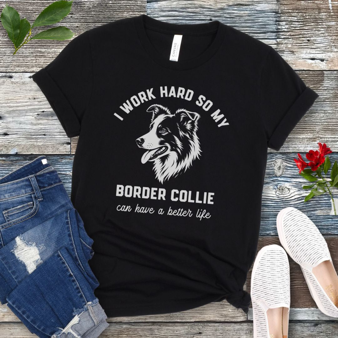 Black unisex t-shirt for Border Collie lovers with breed graphic and humorous text 'I work hard so my Border Collie can have a better life', shown on a wooden surface with jeans and shoes. 