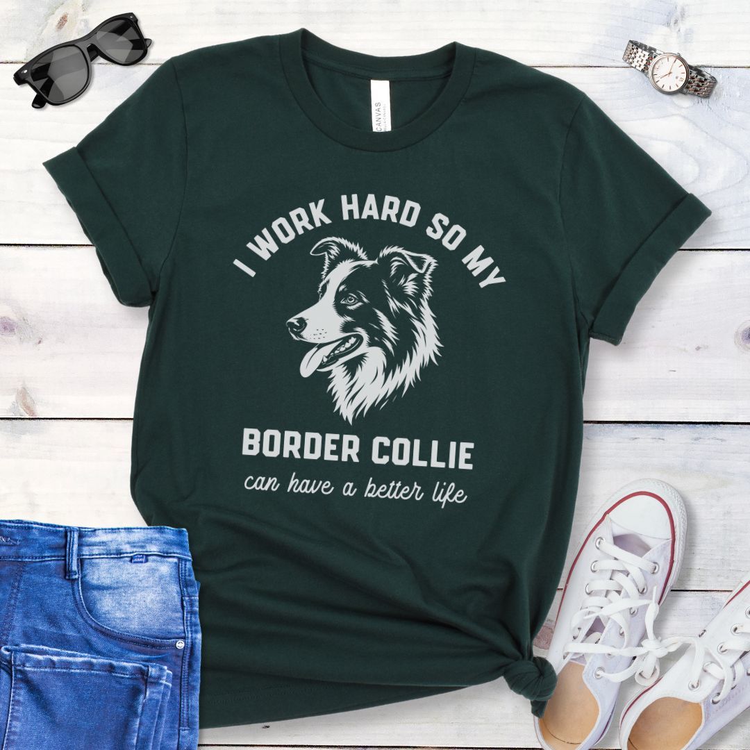 Dark green unisex t-shirt for Border Collie lovers with breed graphic and humorous text 'I work hard so my Border Collie can have a better life', shown on a wooden surface with jeans and shoes. 